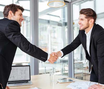 two men shaking hands across a meeting room table